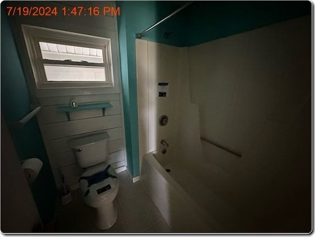 bathroom featuring tile patterned flooring, toilet, and shower / washtub combination