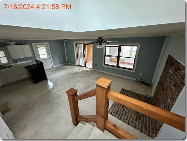 carpeted living room featuring a wealth of natural light, wooden walls, and ceiling fan