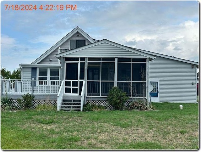 rear view of property featuring a lawn and a sunroom