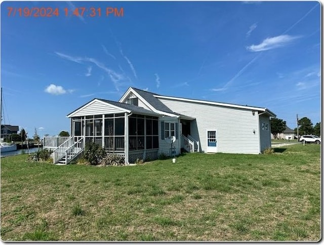 rear view of house with a yard and a sunroom