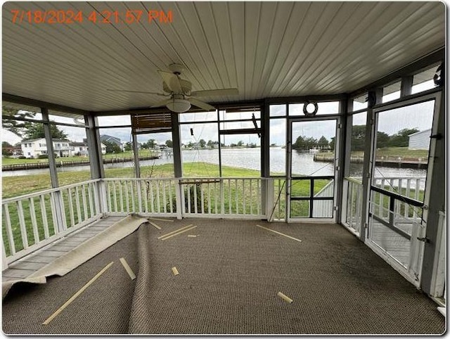 unfurnished sunroom featuring a wealth of natural light, ceiling fan, and a water view