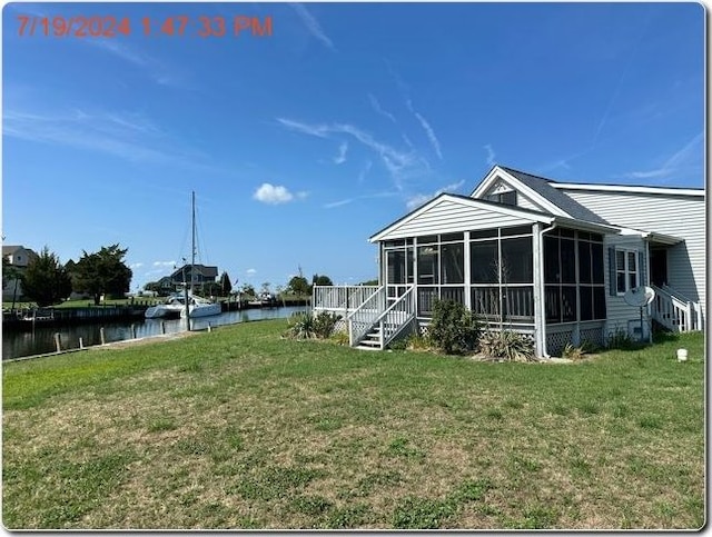 view of yard with a sunroom and a water view