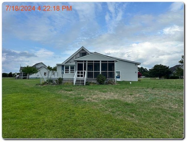 rear view of property featuring a sunroom, a deck, and a yard