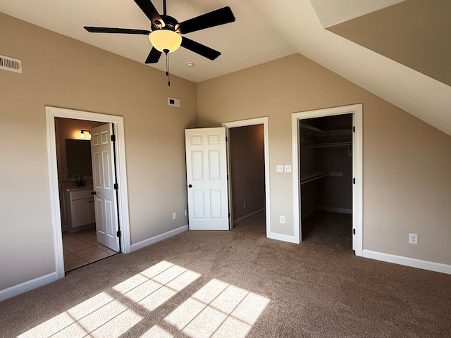 unfurnished bedroom with carpet, visible vents, ensuite bath, vaulted ceiling, and a spacious closet