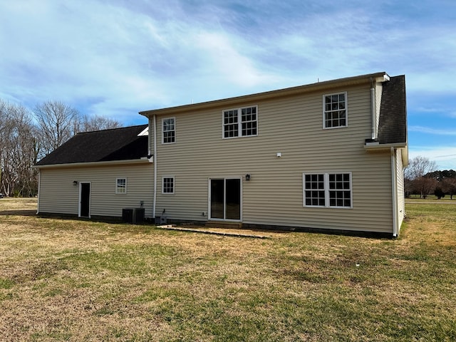 back of house featuring a lawn, central AC, and roof with shingles