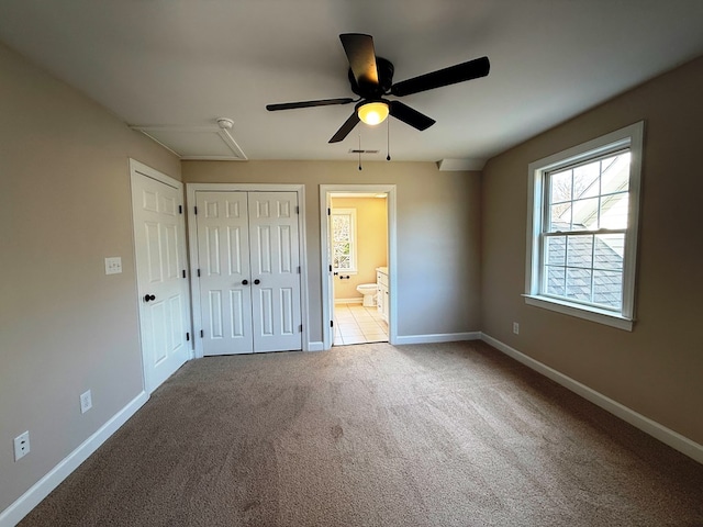 unfurnished bedroom featuring ensuite bath, carpet flooring, baseboards, and a closet