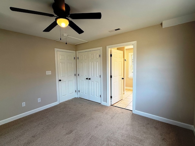 unfurnished bedroom featuring visible vents, carpet floors, baseboards, attic access, and ceiling fan