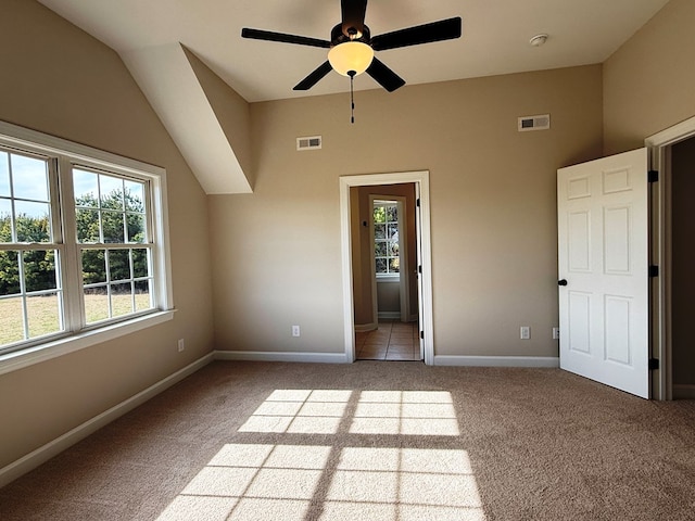 empty room with vaulted ceiling, carpet, and visible vents