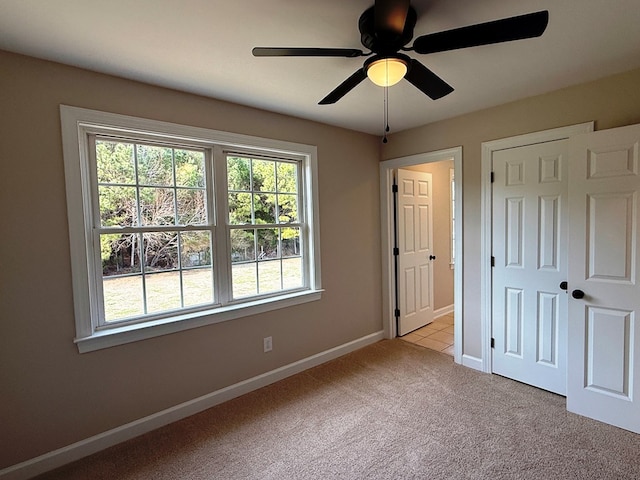 unfurnished bedroom featuring carpet flooring, a ceiling fan, baseboards, and a closet