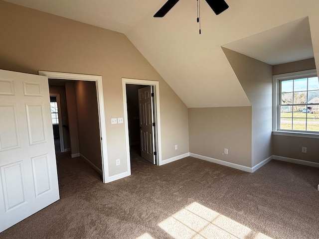 additional living space with dark carpet, a ceiling fan, baseboards, and vaulted ceiling