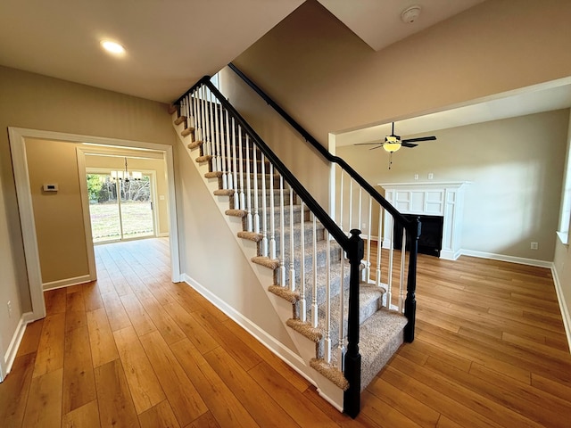 staircase featuring hardwood / wood-style flooring, a ceiling fan, and baseboards