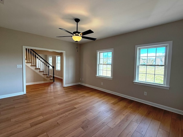 spare room with baseboards, a healthy amount of sunlight, and wood finished floors