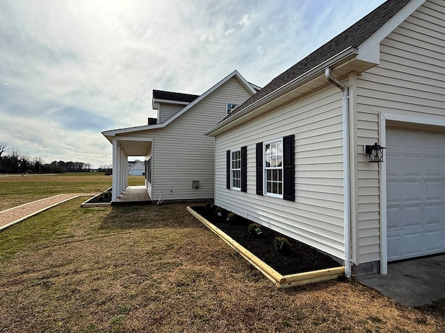 view of side of property with an attached garage, a lawn, and roof with shingles