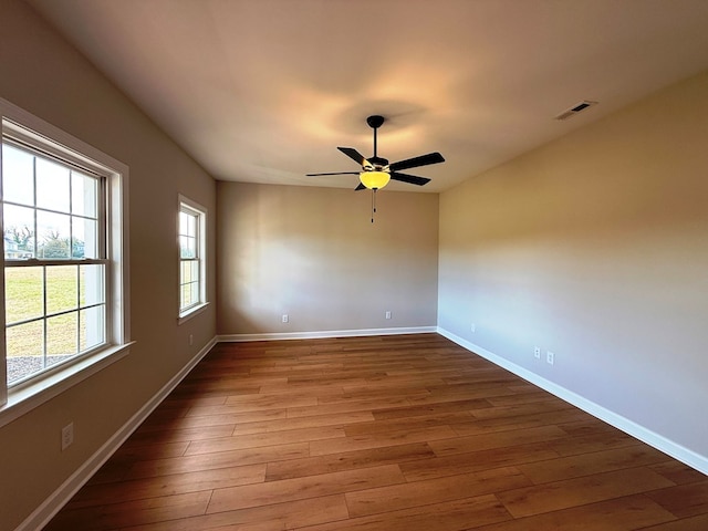 spare room featuring ceiling fan, wood finished floors, visible vents, and baseboards