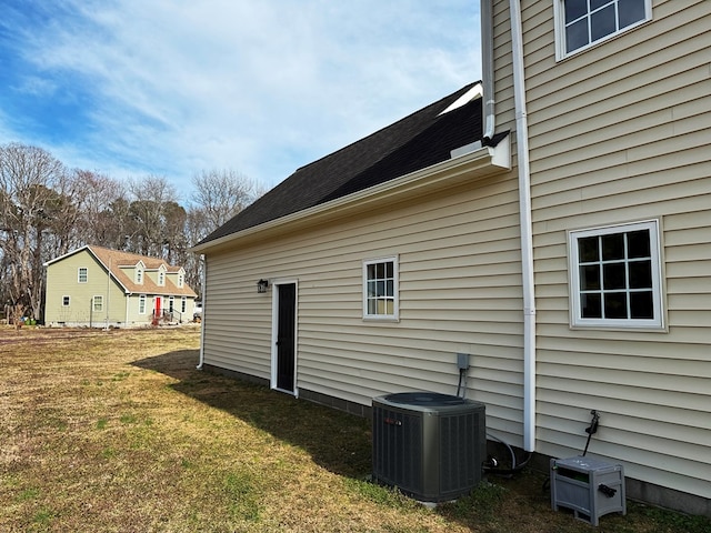 view of side of home with a yard and central AC