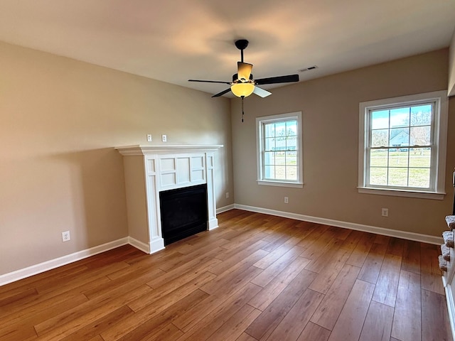 unfurnished living room with visible vents, a fireplace, baseboards, and wood finished floors