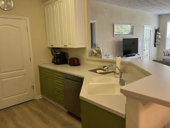 kitchen featuring dishwashing machine, light hardwood / wood-style floors, kitchen peninsula, and white cabinetry