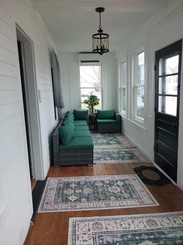 sunroom featuring plenty of natural light, a wall unit AC, and a chandelier