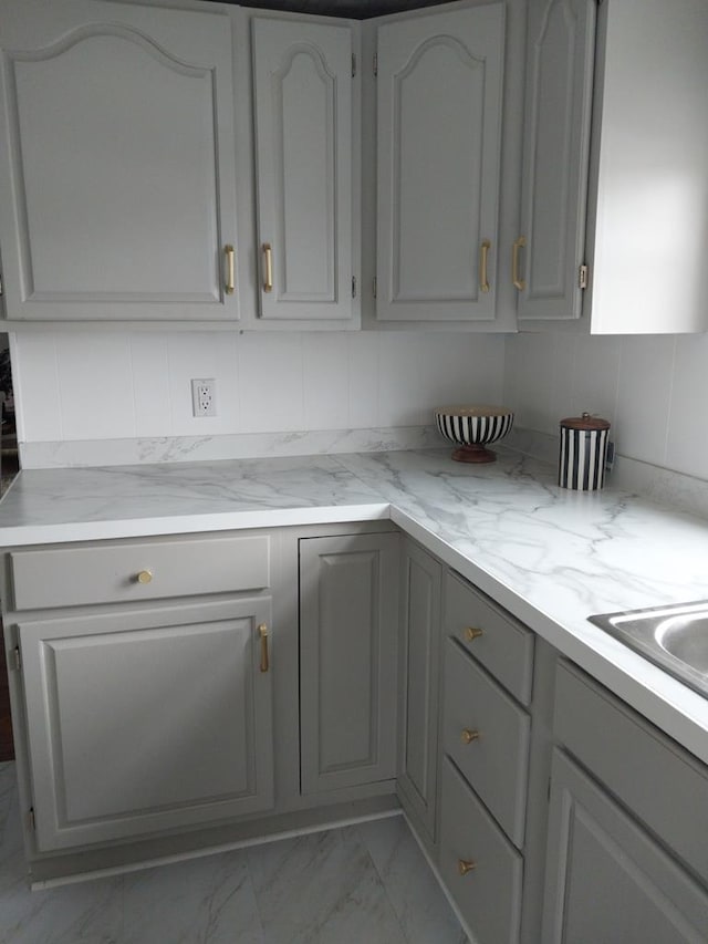 kitchen featuring gray cabinets, sink, and backsplash