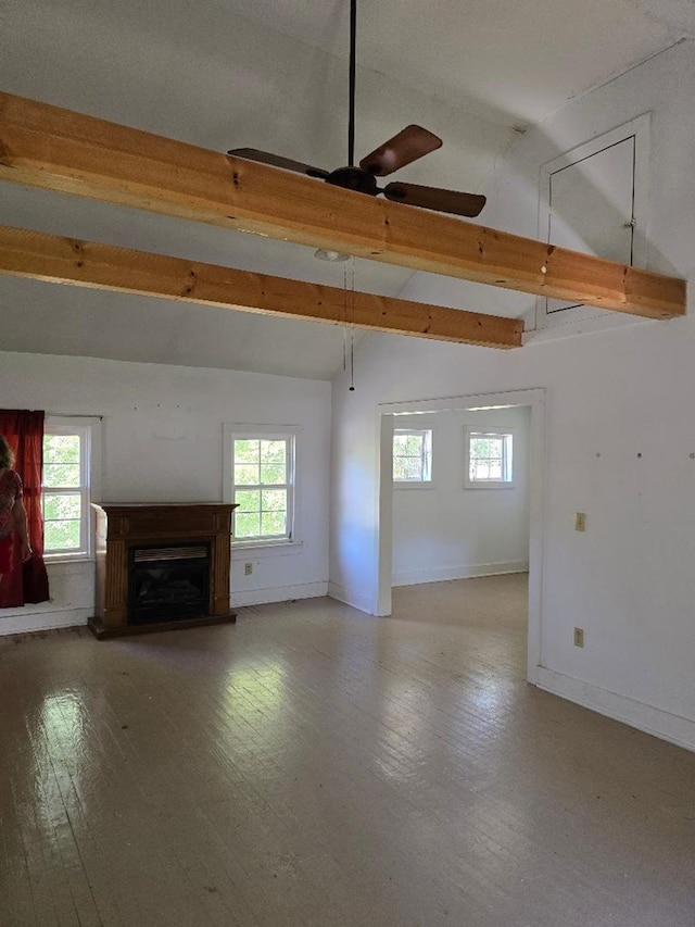 unfurnished living room with lofted ceiling with beams, a healthy amount of sunlight, and ceiling fan