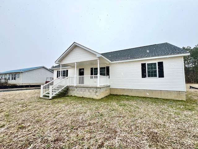 rear view of house featuring a yard and covered porch