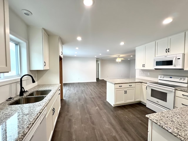 kitchen featuring white cabinetry, sink, kitchen peninsula, light stone countertops, and white appliances