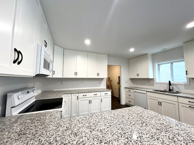 kitchen with white cabinetry, sink, light stone counters, and white appliances