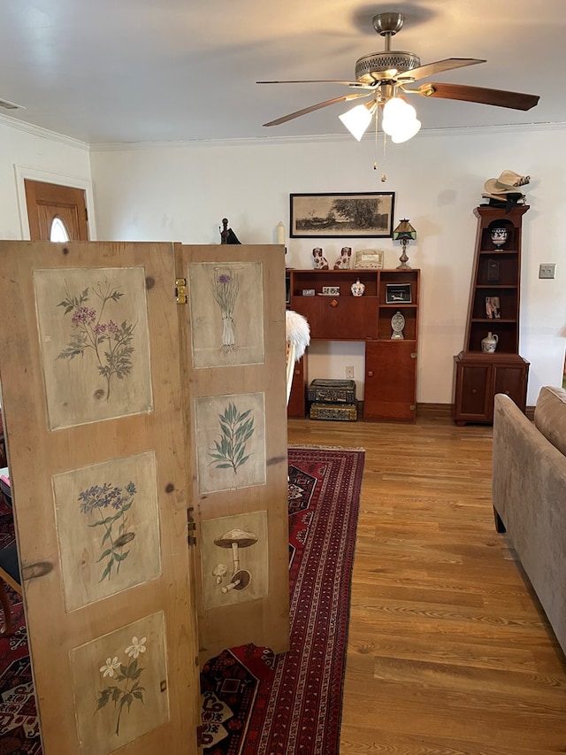 living room with wood-type flooring, ceiling fan, and crown molding