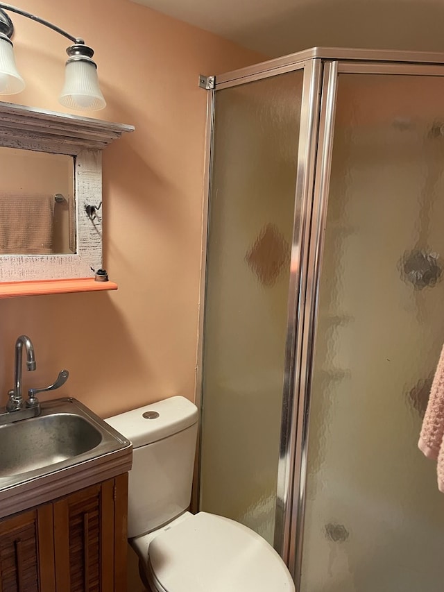 bathroom featuring toilet, an enclosed shower, and sink