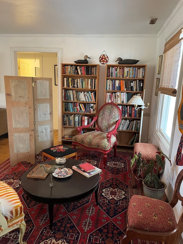 living area featuring hardwood / wood-style floors and crown molding