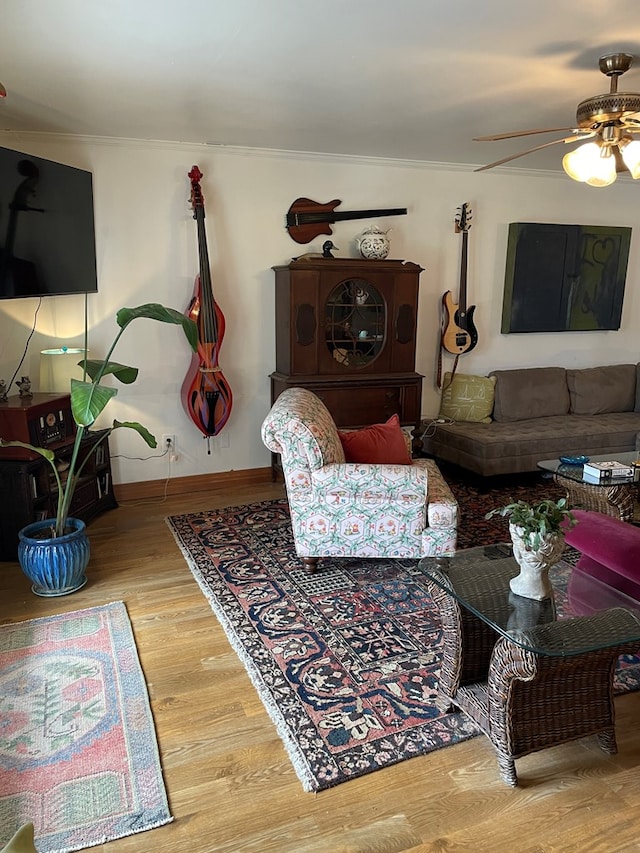 living room featuring wood-type flooring, ceiling fan, and ornamental molding