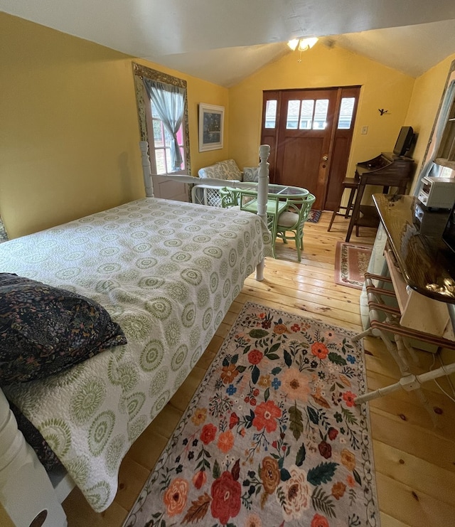 bedroom with light wood-type flooring, lofted ceiling, and multiple windows