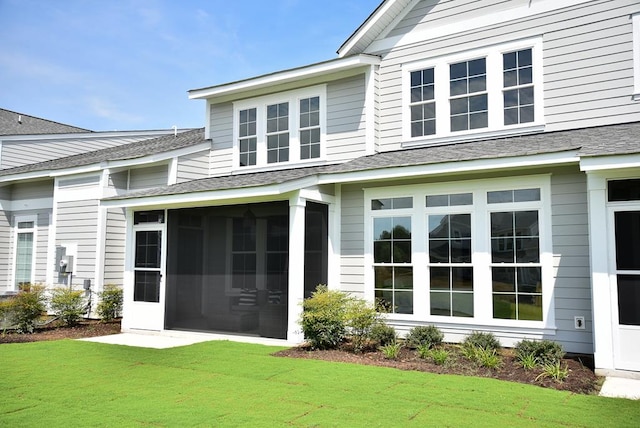 back of property with a sunroom and a yard