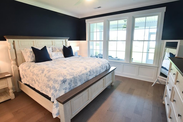 bedroom with ornamental molding, multiple windows, and dark wood-type flooring