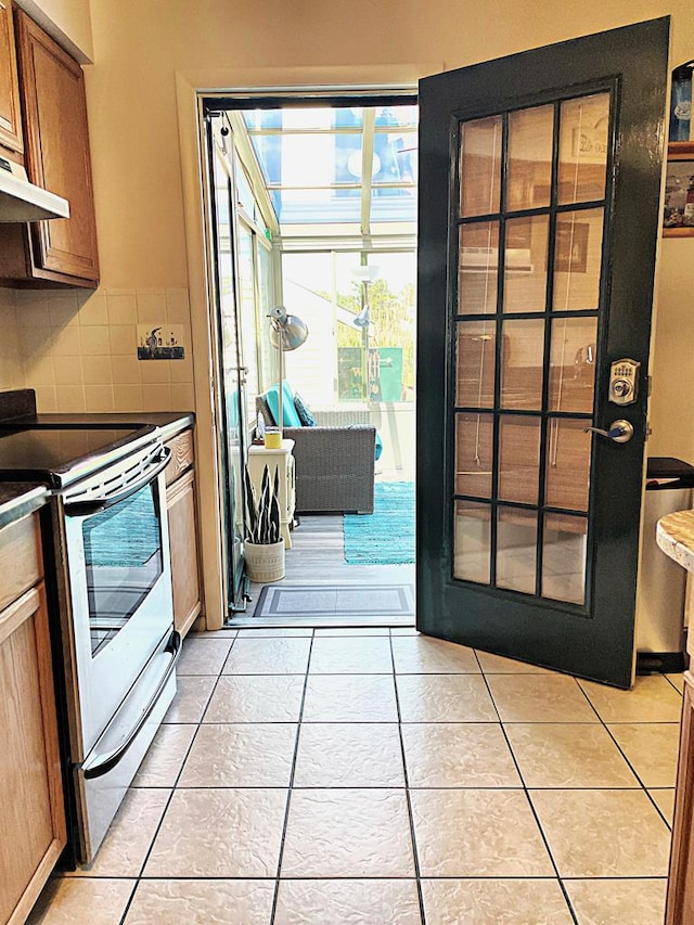 kitchen featuring decorative backsplash, white range with electric stovetop, and light tile patterned flooring