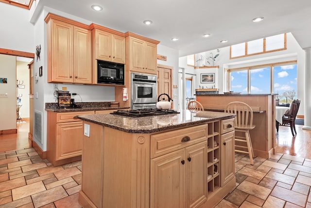 5095 Blake Point Rd, Chincoteague, VA 23336 - kitchen featuring black appliances, a center island, light brown cabinets, stone tile flooring, and recessed lighting