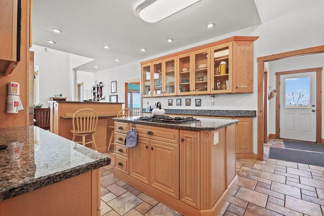 5095 Blake Point Rd, Chincoteague, VA 23336 - kitchen with stainless steel gas stovetop, stone tile flooring, glass insert cabinets, a center island, and recessed lighting