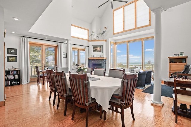 5095 Blake Point Rd, Chincoteague, VA 23336 - dining space featuring light wood finished floors, decorative columns, a fireplace, a high ceiling, and recessed lighting