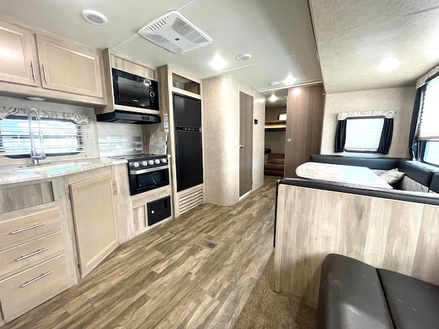 kitchen featuring visible vents, wood finished floors, light countertops, fridge, and black microwave