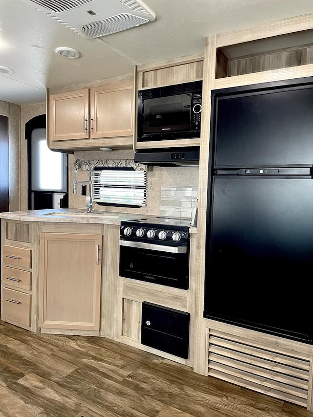 kitchen with light countertops, decorative backsplash, light brown cabinetry, a sink, and black appliances