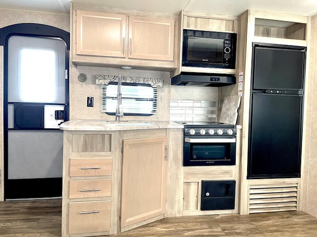 kitchen with light countertops, black appliances, light brown cabinets, and range hood