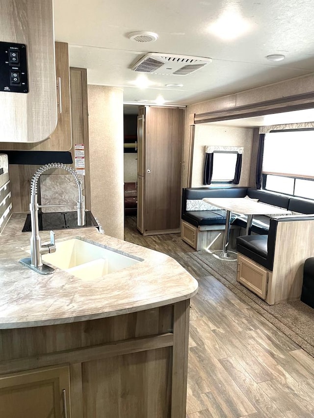 kitchen with light countertops, a sink, visible vents, and wood finished floors