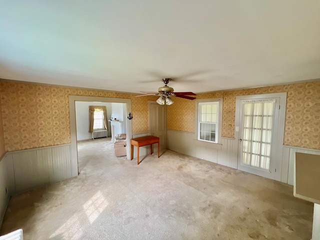 empty room featuring a wainscoted wall, wallpapered walls, and radiator