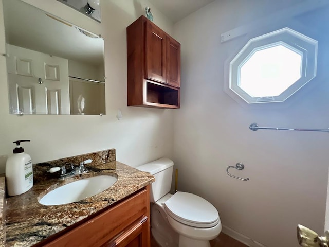 bathroom with toilet, a shower, and vanity