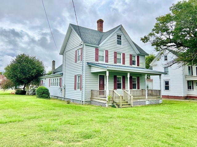 view of front facade featuring a front lawn, roof with shingles, covered porch, and a chimney