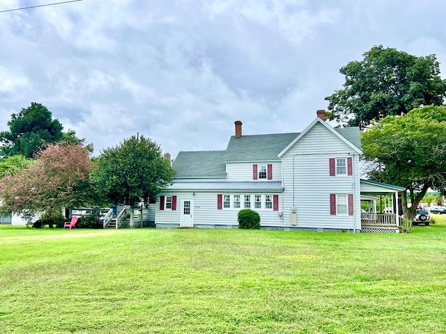 back of house with a shingled roof, a yard, and a chimney