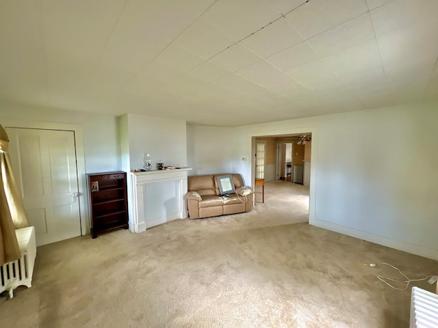 unfurnished living room with light colored carpet and radiator heating unit