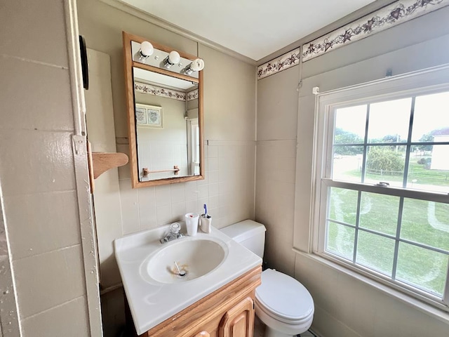 bathroom with toilet, tile walls, ornamental molding, and vanity