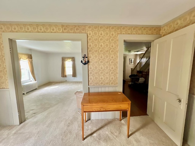 corridor with wainscoting, stairway, radiator, light carpet, and wallpapered walls