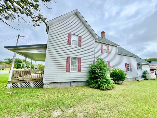 back of property with a yard, a chimney, and a shingled roof